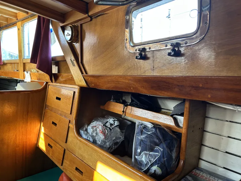 Slide: The Image of Wooden interior of a 1979 Cape George 36 sailboat with storage drawers and porthole. - 16