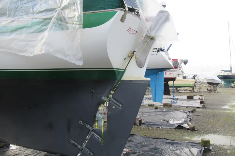 Slide: The Image of 1979 Cape George 36 sailboat on dry dock, covered and secured, with visible rudder. - 25