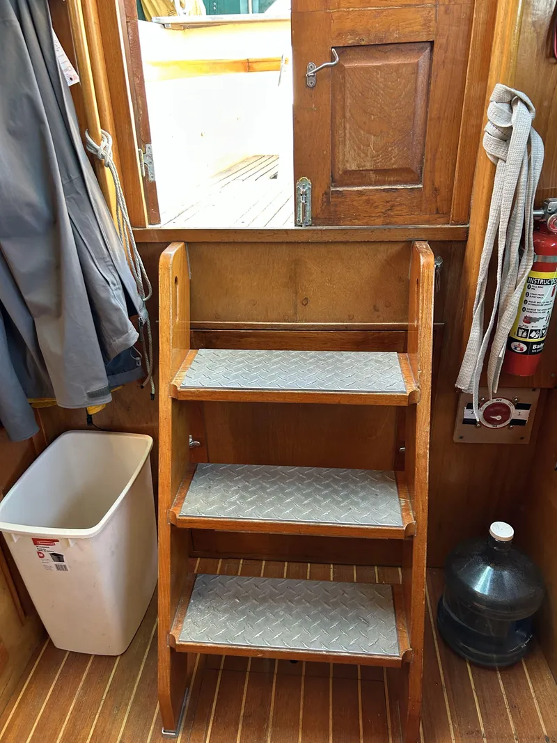 Slide: The Image of Wooden interior stairs on a 1979 Cape George 36 sailboat, with safety equipment nearby. - 4
