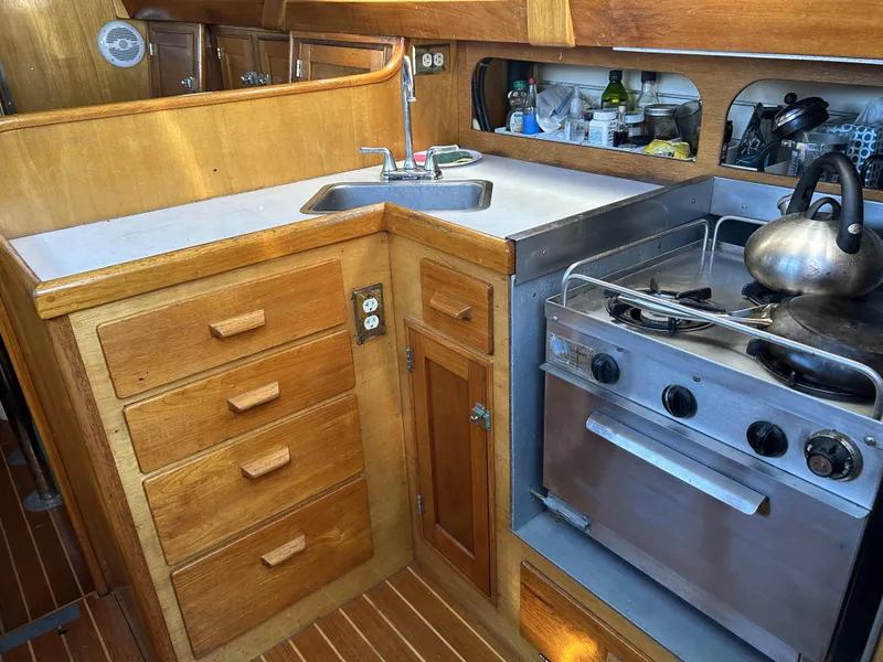 Slide: The Image of 1979 Cape George 36 yacht kitchen with wooden cabinetry, stove, and sink. - 9