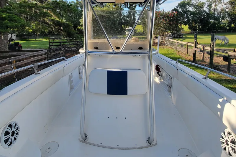 Slide: The Image of 2012 Carolina Skiff 24 boat interior with seating and railing, set in a rural landscape. - 11