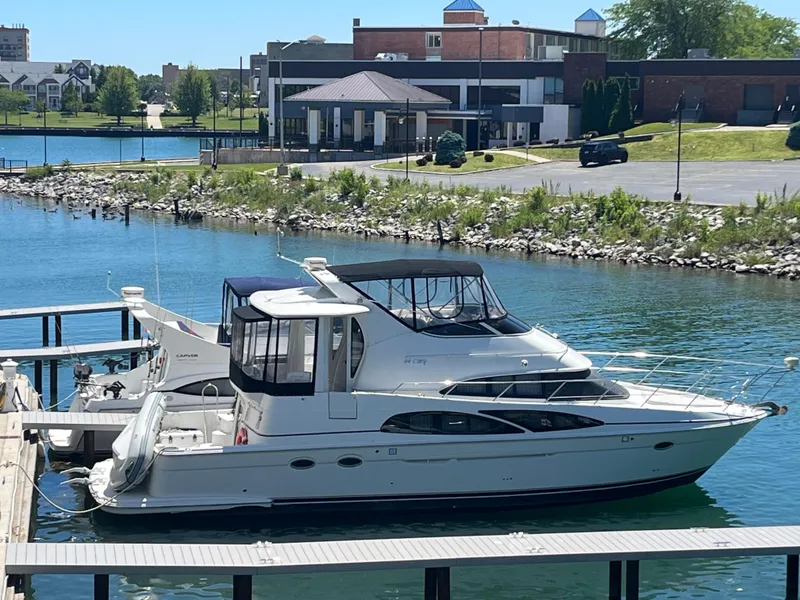 The Image of 2005 Carver 44 CMY yacht docked in a marina with scenic waterfront view. - 1