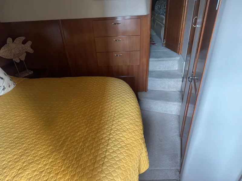 Slide: The Image of Interior of 2005 Carver 44 CMY with yellow bedspread, wooden cabinets, and carpeted stairs. - 4