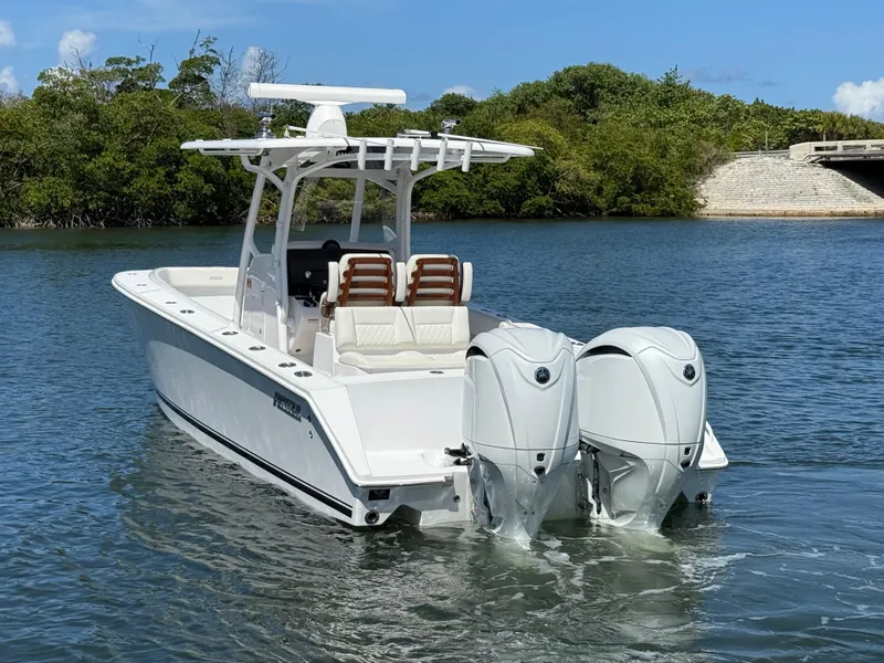 Slide: The Image of 2023 Jupiter 30 boat with dual engines on calm water, surrounded by greenery. - 2