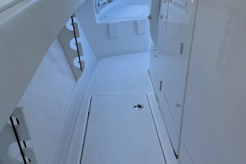 Slide: The Image of Interior view of a 2023 Jupiter 30 boat, featuring sleek white surfaces and storage compartments. - 7