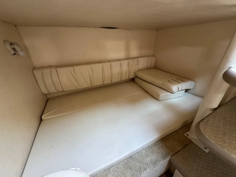 Slide: The Image of 2003 Sea Ray 290 Amberjack cabin interior with beige cushions and compact layout. - 12