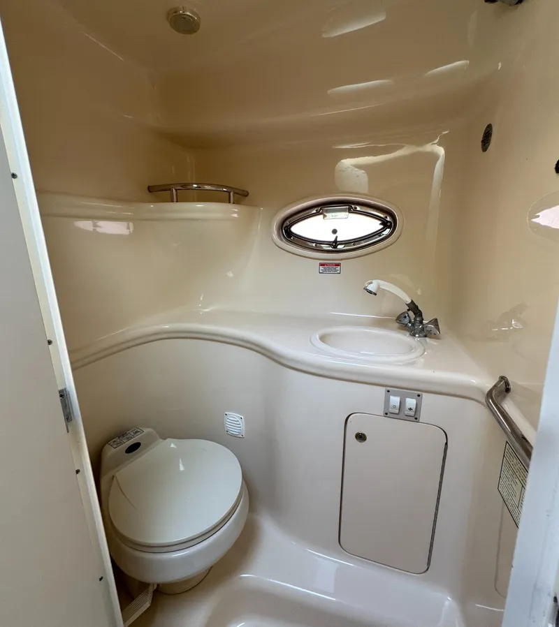 Slide: The Image of 2003 Sea Ray 290 Amberjack boat bathroom with toilet, sink, and porthole window. - 14