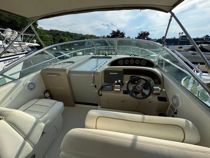 Slide: The Image of 2003 Sea Ray 290 Amberjack cockpit with steering wheel, gauges, and seating, docked at marina. - 7