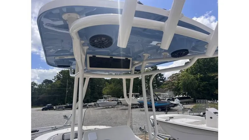 Slide: The Image of 2025 Carolina Skiff 24 Ultra Elite boat with blue T-top and speakers, docked outdoors. - 12