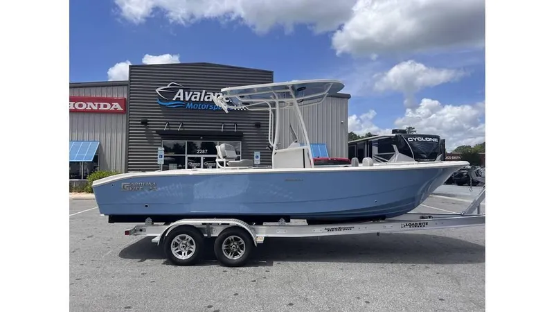 Slide: The Image of 2025 Carolina Skiff 24 Ultra Elite boat on trailer, parked outside dealership. - 2