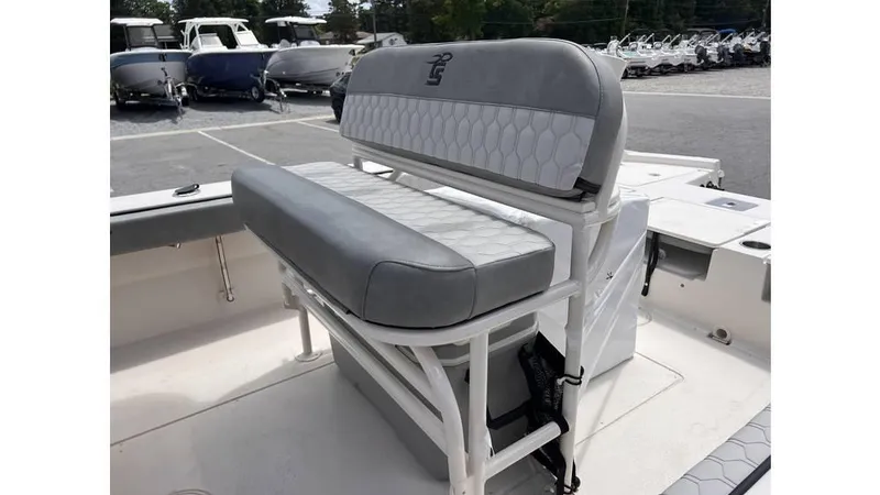 Slide: The Image of 2025 Carolina Skiff 24 Ultra Elite boat seating, featuring gray cushioned bench in a marina setting. - 6