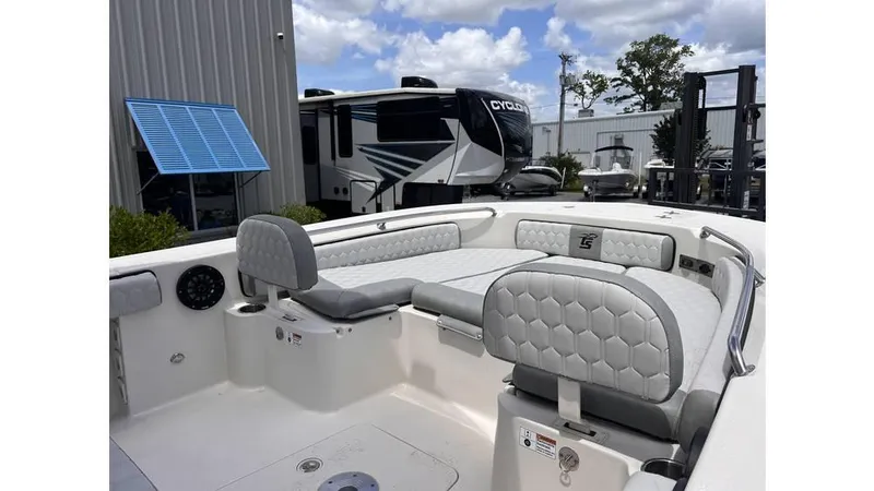 Slide: The Image of 2025 Carolina Skiff 24 Ultra Elite boat interior with cushioned seating, parked near RV. - 9