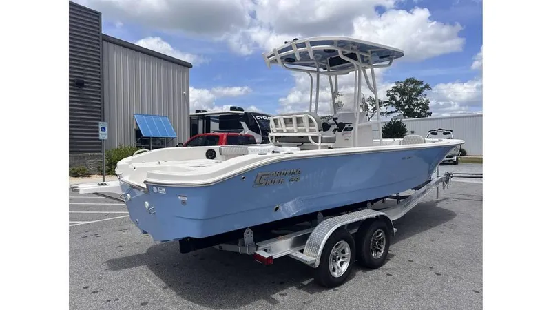 Slide: The Image of 2025 Carolina Skiff 24 Ultra Elite boat on trailer, parked outdoors under cloudy sky. - 3
