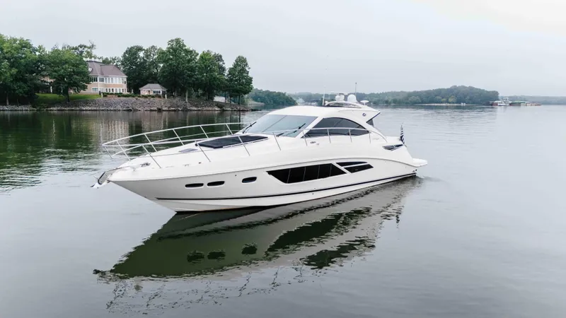 Slide: The Image of 2013 Sea Ray 510 Sundancer yacht cruising on a calm lake near shoreline homes. - 11