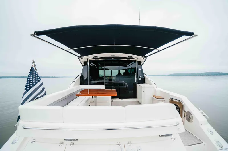 Slide: The Image of 2013 Sea Ray 510 Sundancer yacht with canopy, rear seating, and American flag on calm water. - 31