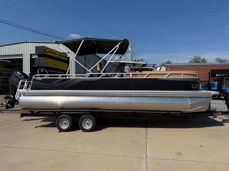 Slide: The Image of 2025 Avalon Venture 85 Versatile rear Bench pontoon boat on trailer, parked outside dealership. - 1