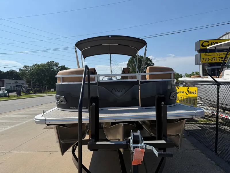 Slide: The Image of 2025 Avalon Venture 85 Versatile rear Bench pontoon boat on trailer, outdoor dealership setting. - 3