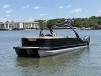 The Image of 2022 Bennington 30 RSRAX2 pontoon boat on a calm lake with buildings in the background. - 1
