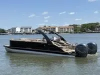 Slide: The Image of 2022 Bennington 30 RSRAX2 pontoon boat on calm water, with buildings in the background. - 5