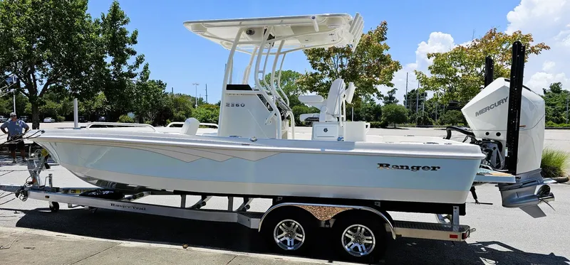 Slide: The Image of 2025 Ranger 2360 Bay boat on trailer, parked outdoors, featuring Mercury engine. - 11
