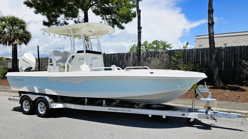 Slide: The Image of 2025 Ranger 2360 Bay boat on trailer, parked outdoors under clear sky. - 2