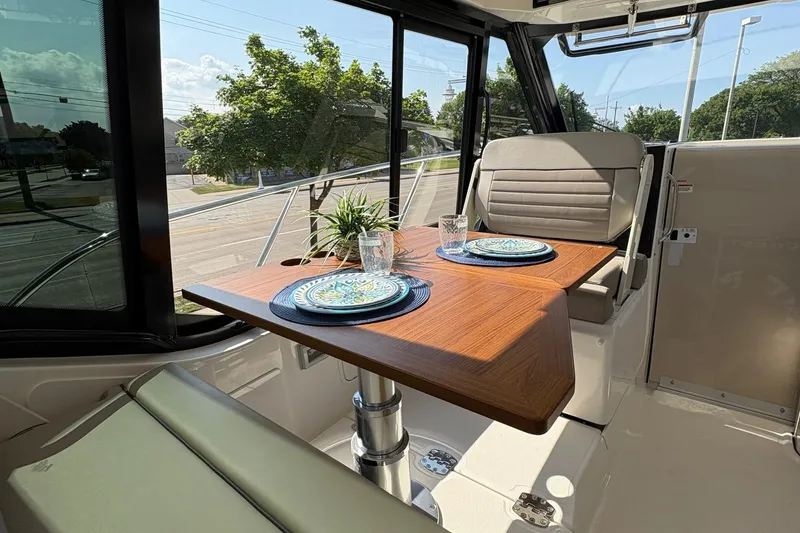 Slide: The Image of 2025 Boston Whaler 365 Conquest interior dining area with wooden table and elegant place settings. - 4