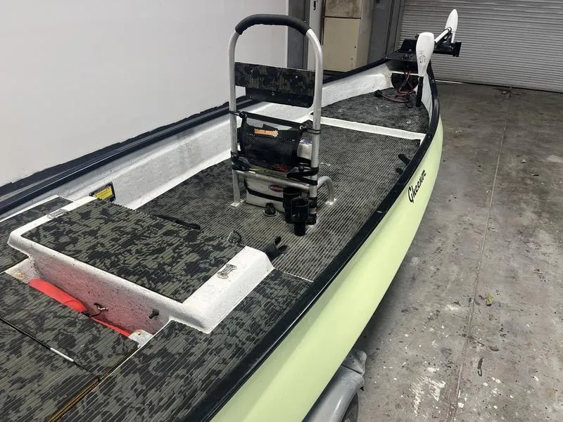 Slide: The Image of 2022 Gheenoe Low Tide 25 boat with camouflage seating and trolling motor in a garage. - 2
