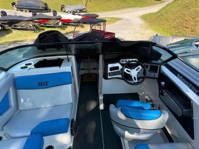Slide: The Image of 2017 MasterCraft NXT22 boat interior with blue and white seating, steering wheel, and dashboard. - 11