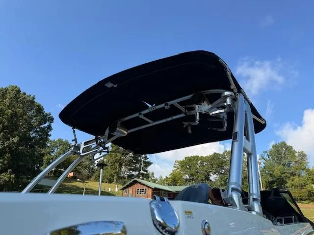 Slide: The Image of 2017 MasterCraft NXT22 boat with canopy, set against a clear blue sky and lush greenery. - 13