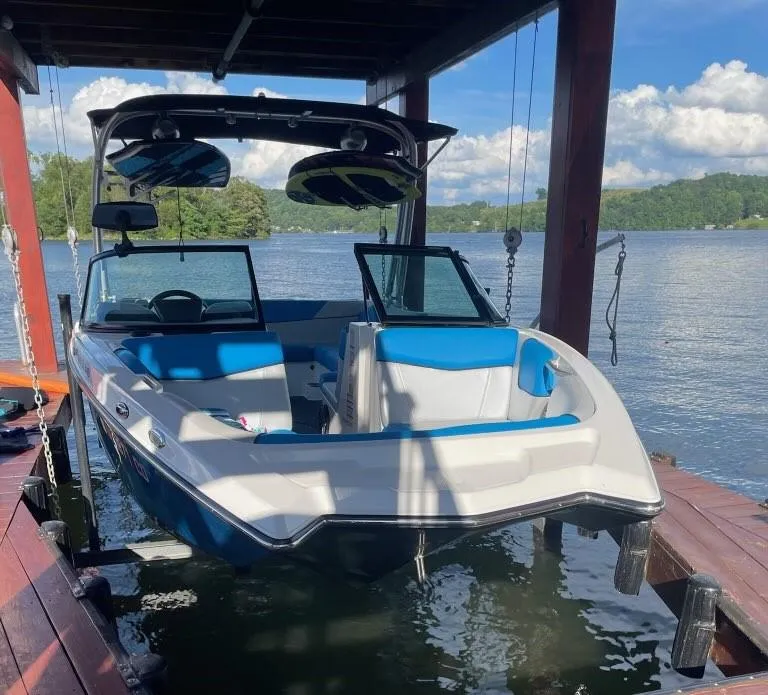 Slide: The Image of 2017 MasterCraft NXT22 boat docked on a serene lake under a wooden canopy. - 3