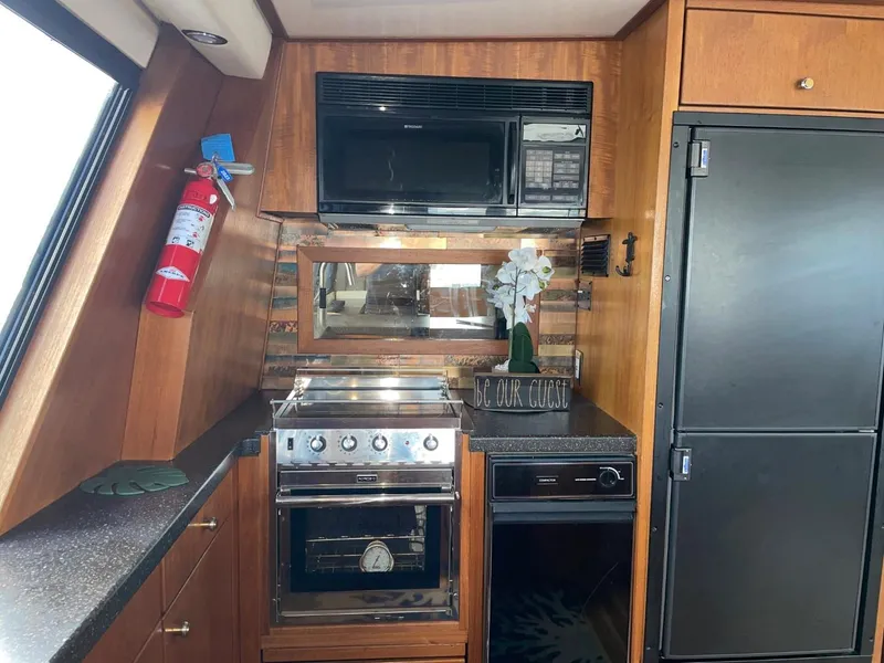 Slide: The Image of 1994 Bayliner 4788 Pilot House Motoryacht kitchen with stove, microwave, and refrigerator. - 14