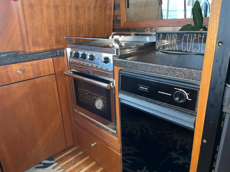 Slide: The Image of 1994 Bayliner 4788 Pilot House Motoryacht kitchen with stove, oven, and wooden cabinetry. - 17