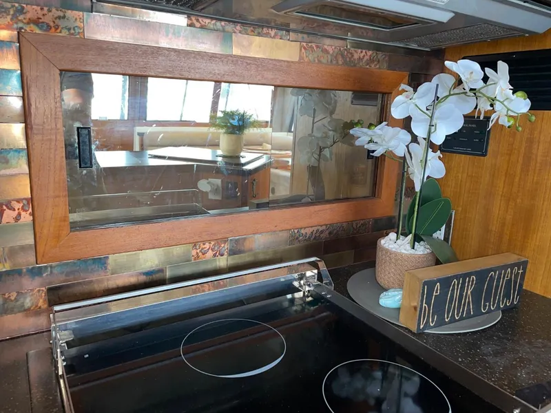 Slide: The Image of 1994 Bayliner 4788 yacht kitchen with stove, decorative orchid, and "Be Our Guest" sign. - 20
