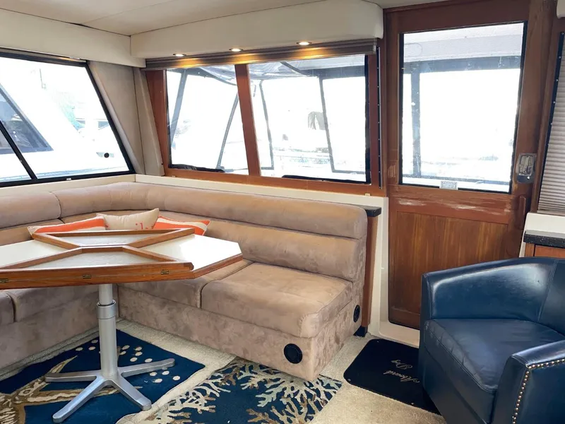 Slide: The Image of 1994 Bayliner 4788 Pilot House Motoryacht interior with beige seating, wooden table, and blue armchair. - 23