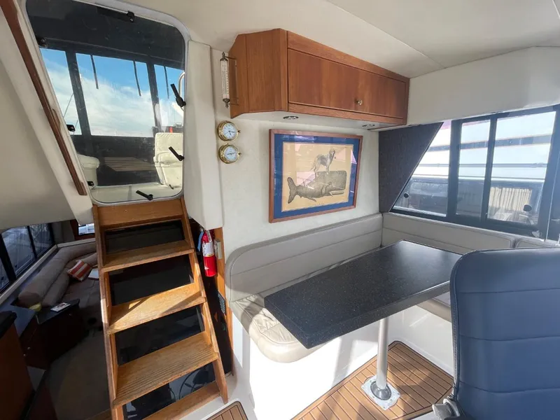 Slide: The Image of 1994 Bayliner 4788 Pilot House Motoryacht interior with dining area and wooden stairs. - 37