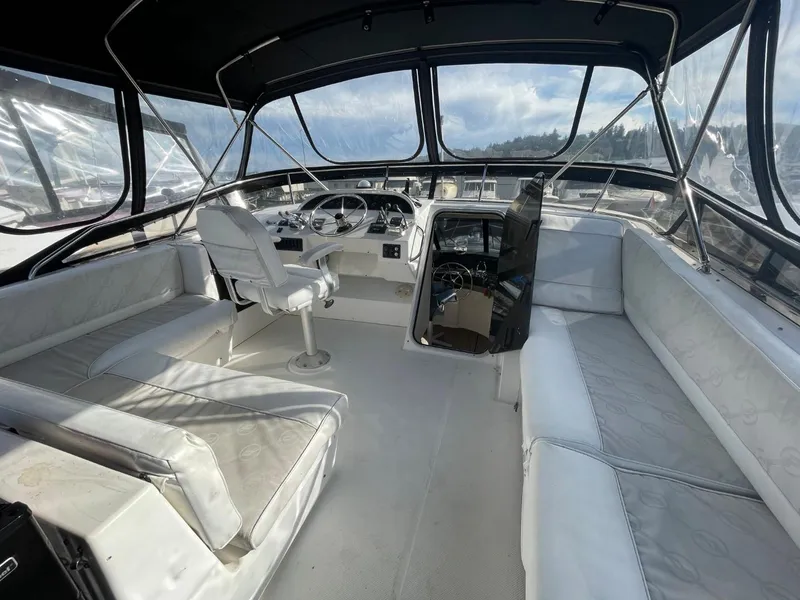 Slide: The Image of 1994 Bayliner 4788 Pilot House Motoryacht interior with white seating and steering console. - 44