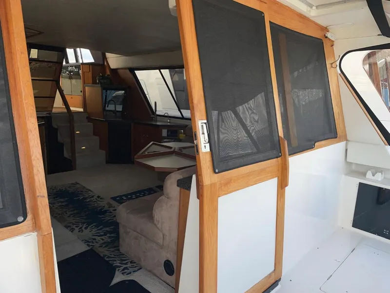 Slide: The Image of Interior view of 1994 Bayliner 4788 Pilot House Motoryacht, featuring cozy seating and wooden accents. - 7