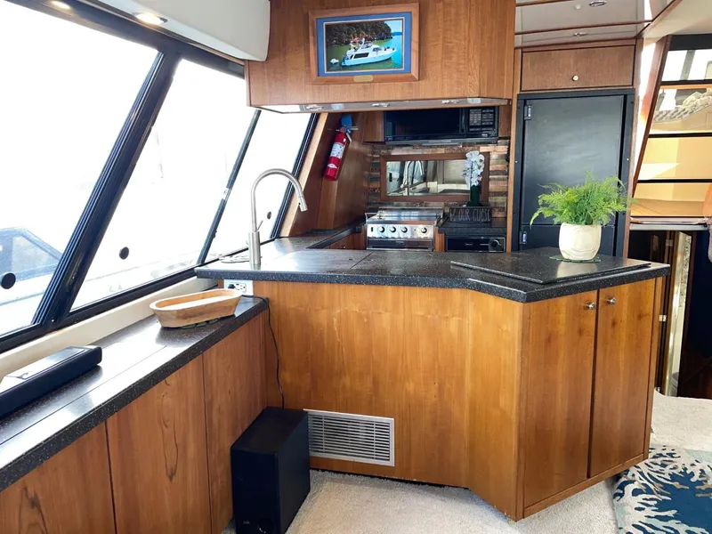Slide: The Image of 1994 Bayliner 4788 Pilot House Motoryacht interior with kitchen, wood cabinetry, and modern appliances. - 9