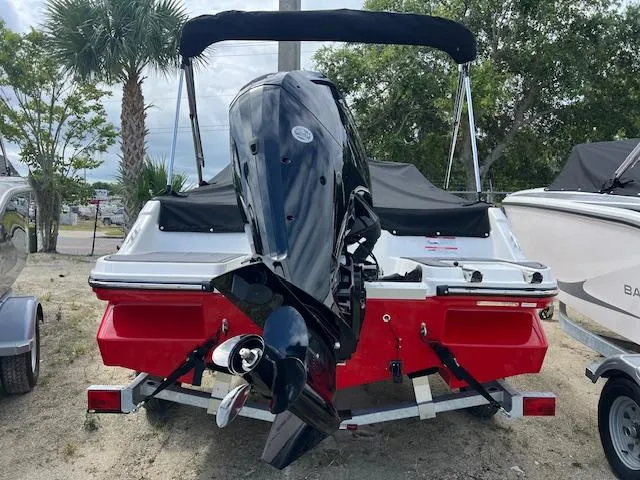 Slide: The Image of 2025 Bayliner Element M17 boat with outboard motor, red and white design, parked outdoors. - 2