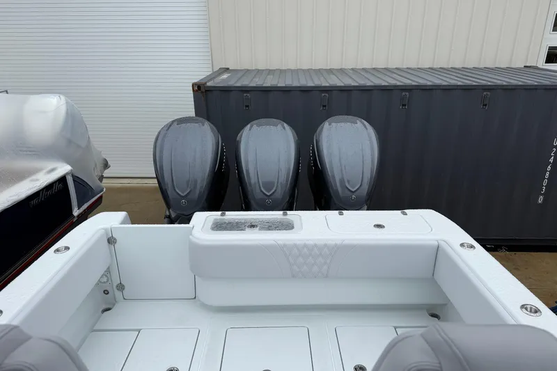 Slide: The Image of 2026 Contender 35 ST boat with triple outboard engines, docked near a storage container. - 8