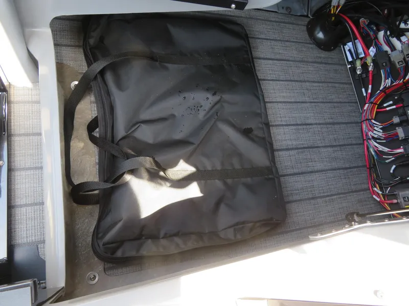 Slide: The Image of Black storage bag and wiring inside Avalon Excalibur Elite Windshield 2026 boat compartment. - 26