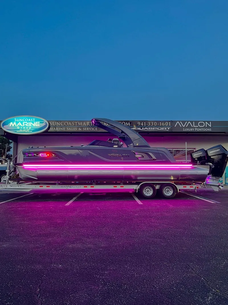 Slide: The Image of 2026 Avalon Excalibur boat with neon lights on a trailer at Suncoast Marine. - 9