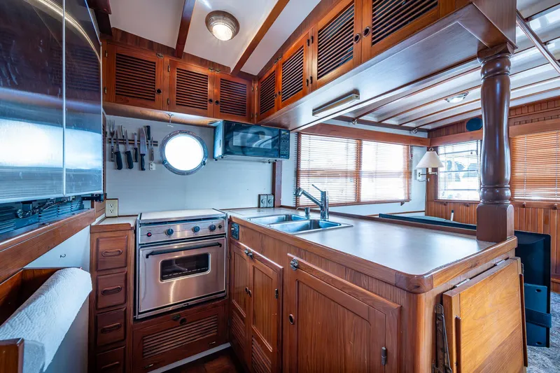 Slide: The Image of 1993 Kadey-Krogen Krogen 42 yacht kitchen with wood cabinetry, stainless steel appliances, and porthole window. - 14