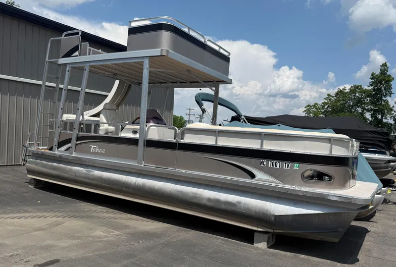The Image of 2011 Tahoe Pontoon Double Decker boat with slide, parked outdoors under a blue sky. - 0
