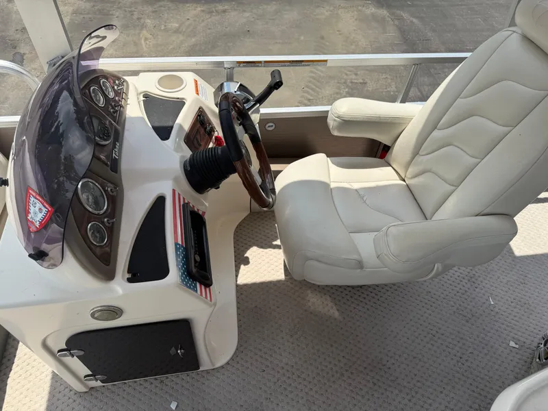Slide: The Image of 2011 Tahoe Pontoon Double Decker helm with white captain's chair and dashboard controls. - 17