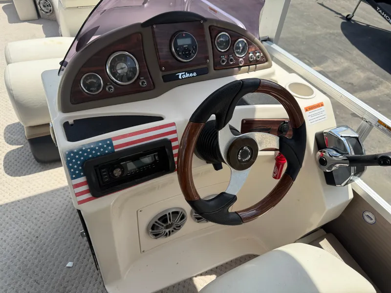 Slide: The Image of 2011 Tahoe Pontoon Double Decker dashboard with steering wheel and American flag detail. - 18