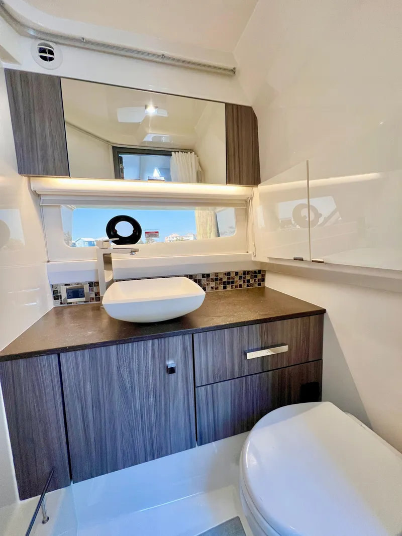 Slide: The Image of 2022 Sea Ray SLX 400 OB bathroom with modern fixtures and wood cabinetry. - 19