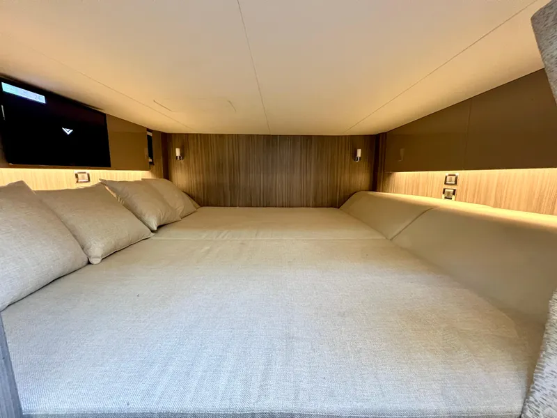 Slide: The Image of 2022 Sea Ray SLX 400 OB cabin interior with cozy bedding and ambient lighting. - 22