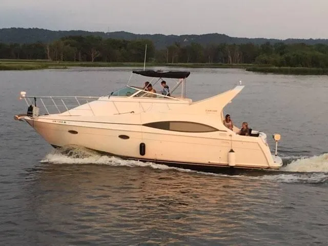 Slide: The Image of 1999 Carver 350 Mariner yacht cruising on a serene lake with passengers onboard. - 13