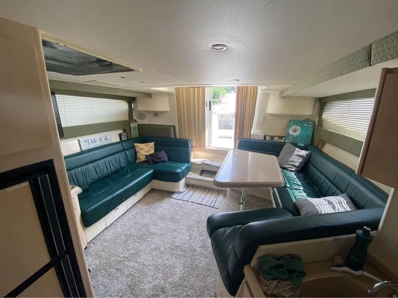 Slide: The Image of Interior of a 1999 Carver 350 Mariner yacht with green seating and a central table. - 15